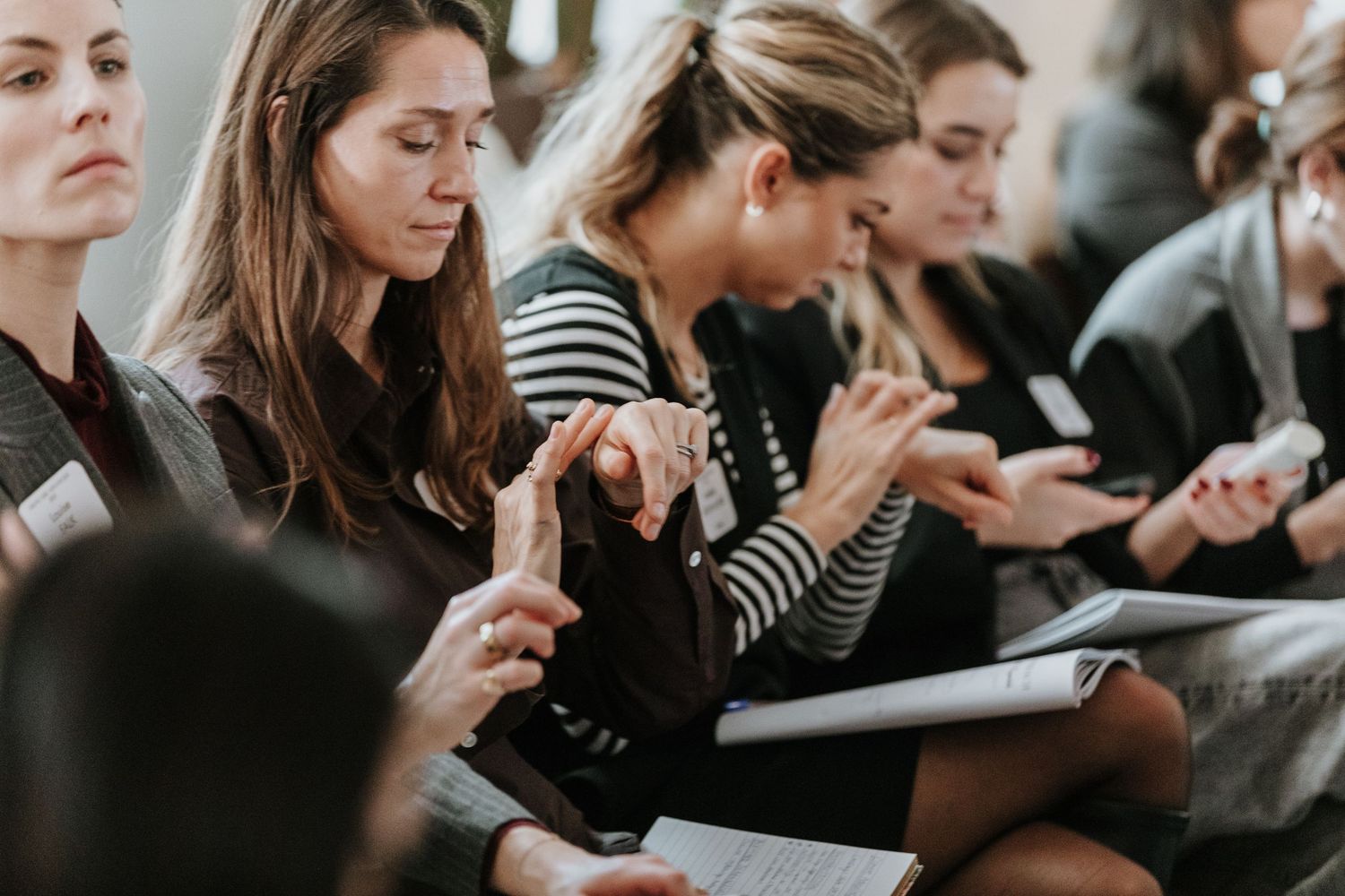 Students taking notes and using mobile devices during a crowded lecture or classroom session.