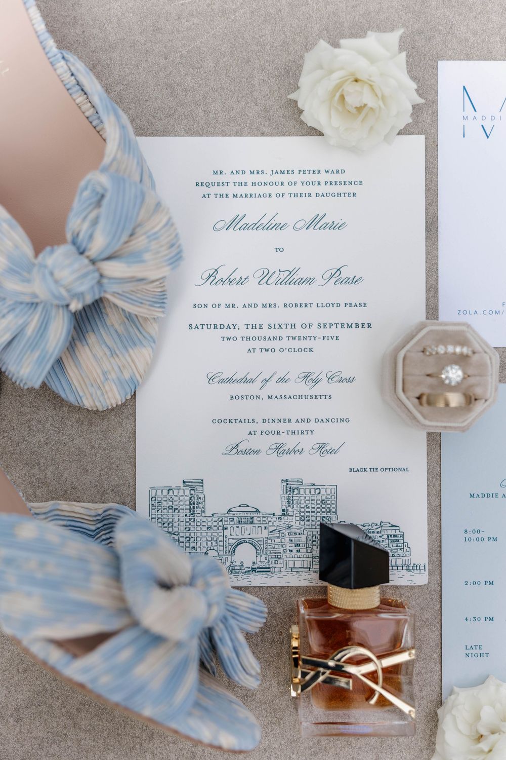 Elegant wedding invitation suite with blue and white striped ribbon and floral details on a neutral background.