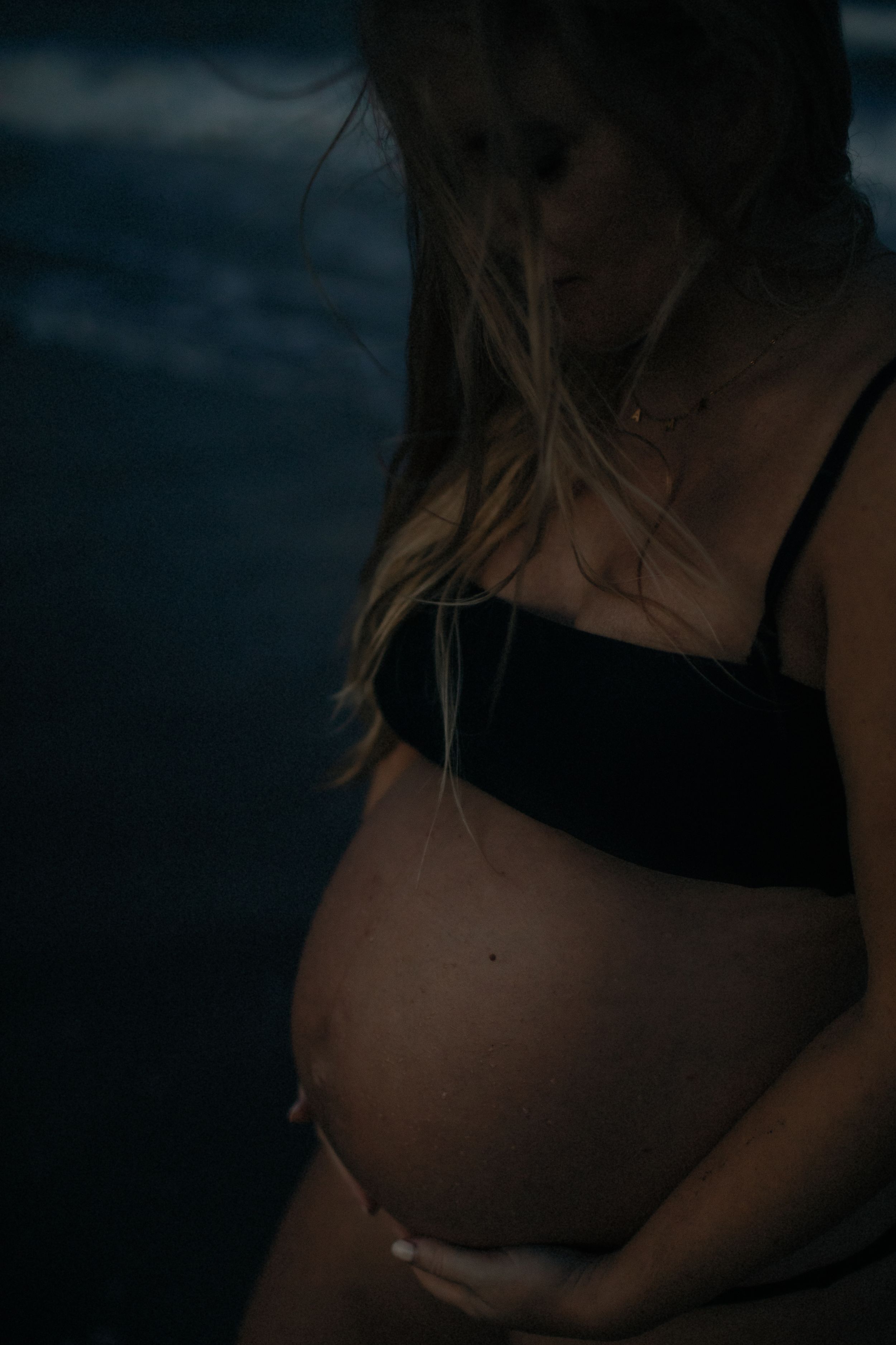 A series of dark moody photos showing a pregnant woman's silhouette in black undergarments against a shadowy background.