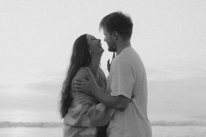 A romantic black and white photo of a couple embracing on the beach at sunset.