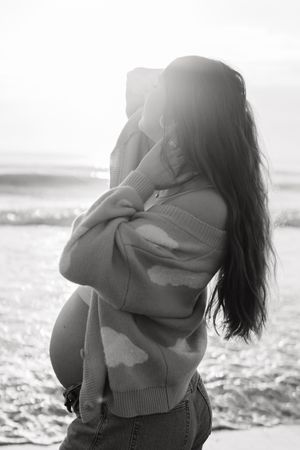 Black and white romantic sequence of a couple embracing on a beach at sunset with waves in the background.
