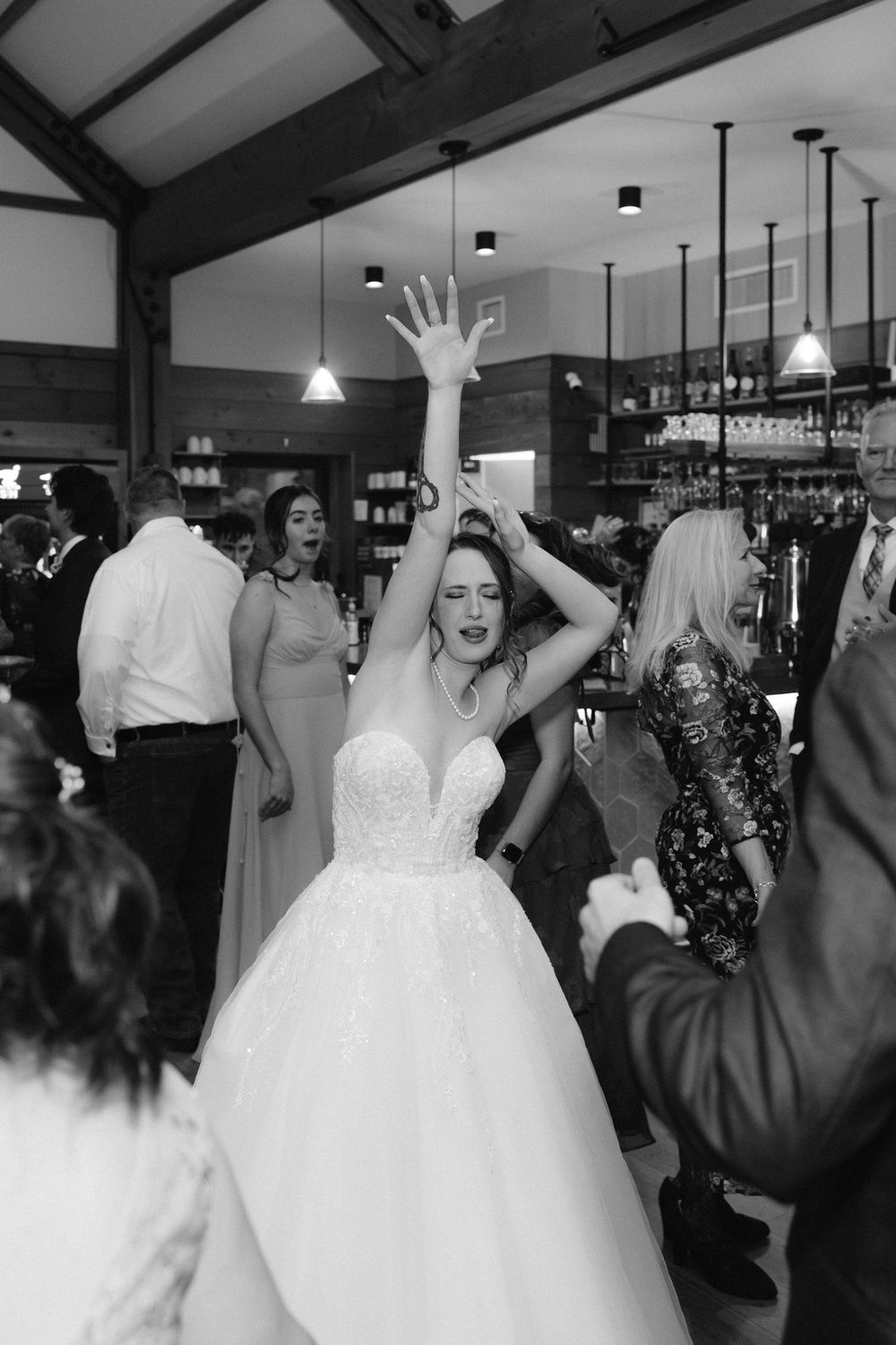 Wedding reception guests dancing and celebrating on the dance floor with a bride in a white ballgown dress.