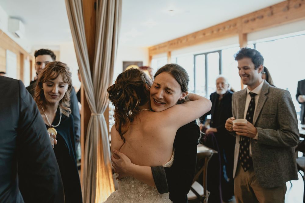 Wedding guests laugh and celebrate during a joyful candid moment at an indoor reception.
