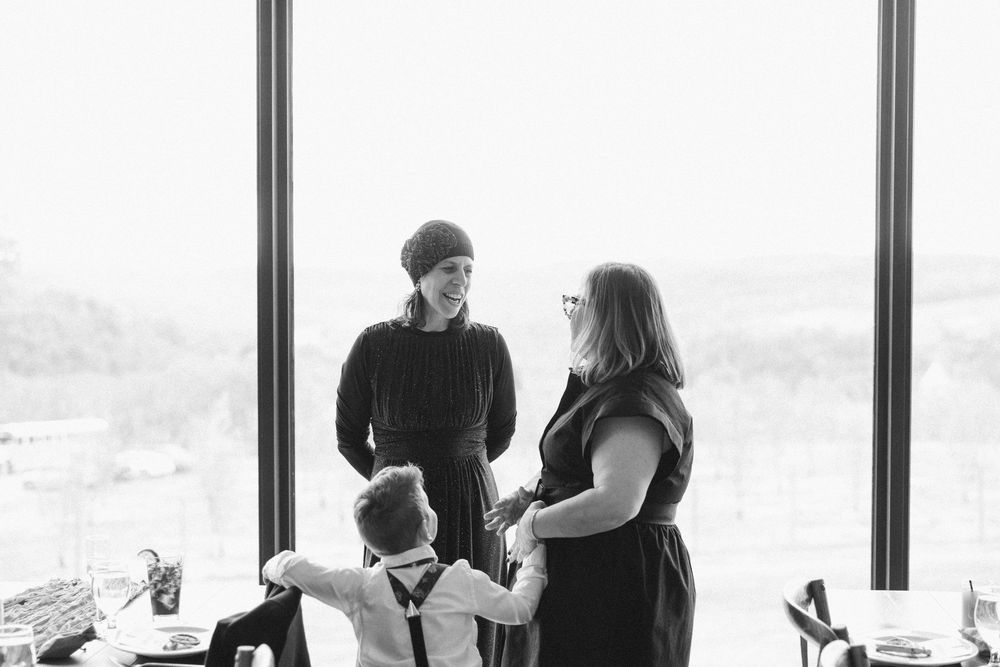 A silhouetted group gathers near large windows overlooking a scenic mountain landscape.