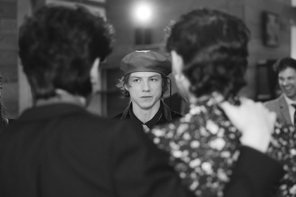 Black and white photo of guests dancing and mingling at an evening wedding reception.
