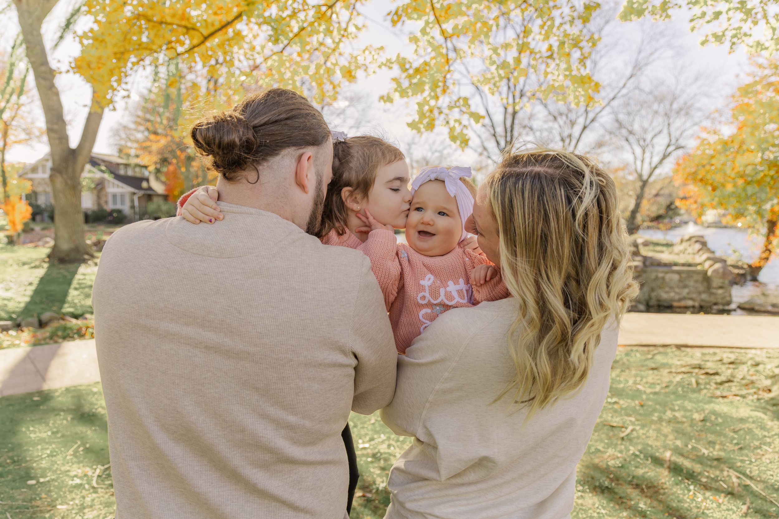A romantic couple embraces outdoors during a golden autumn afternoon in a park setting.