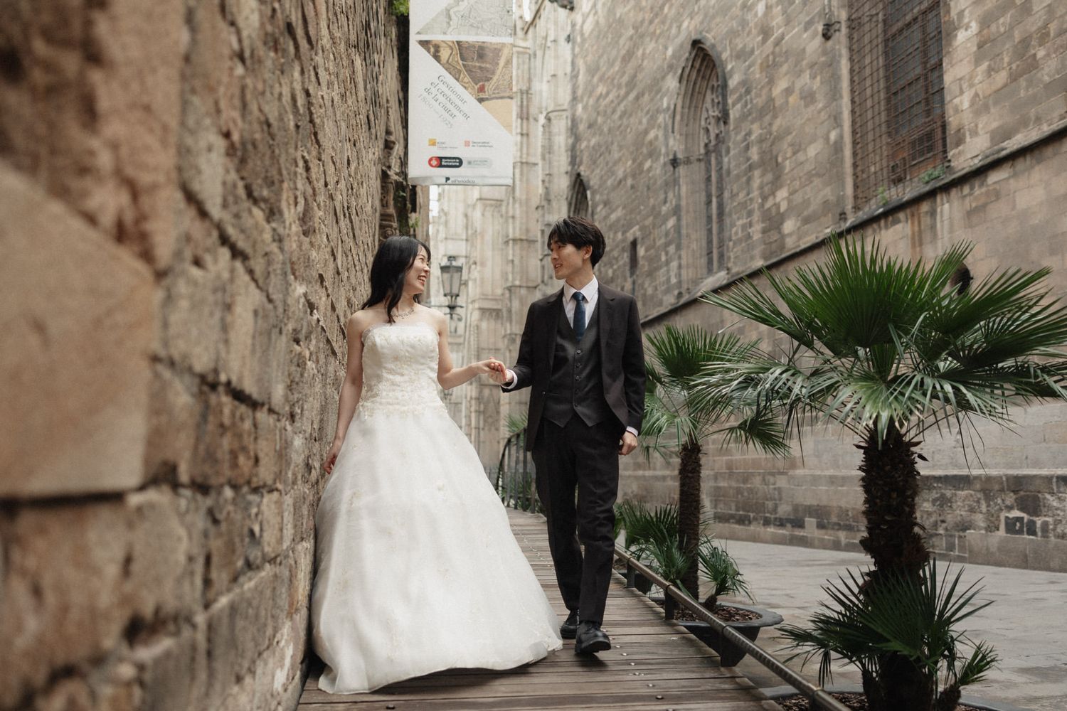 Wedding couple walks along ancient stone walls and cobblestone streets in a historic European city.