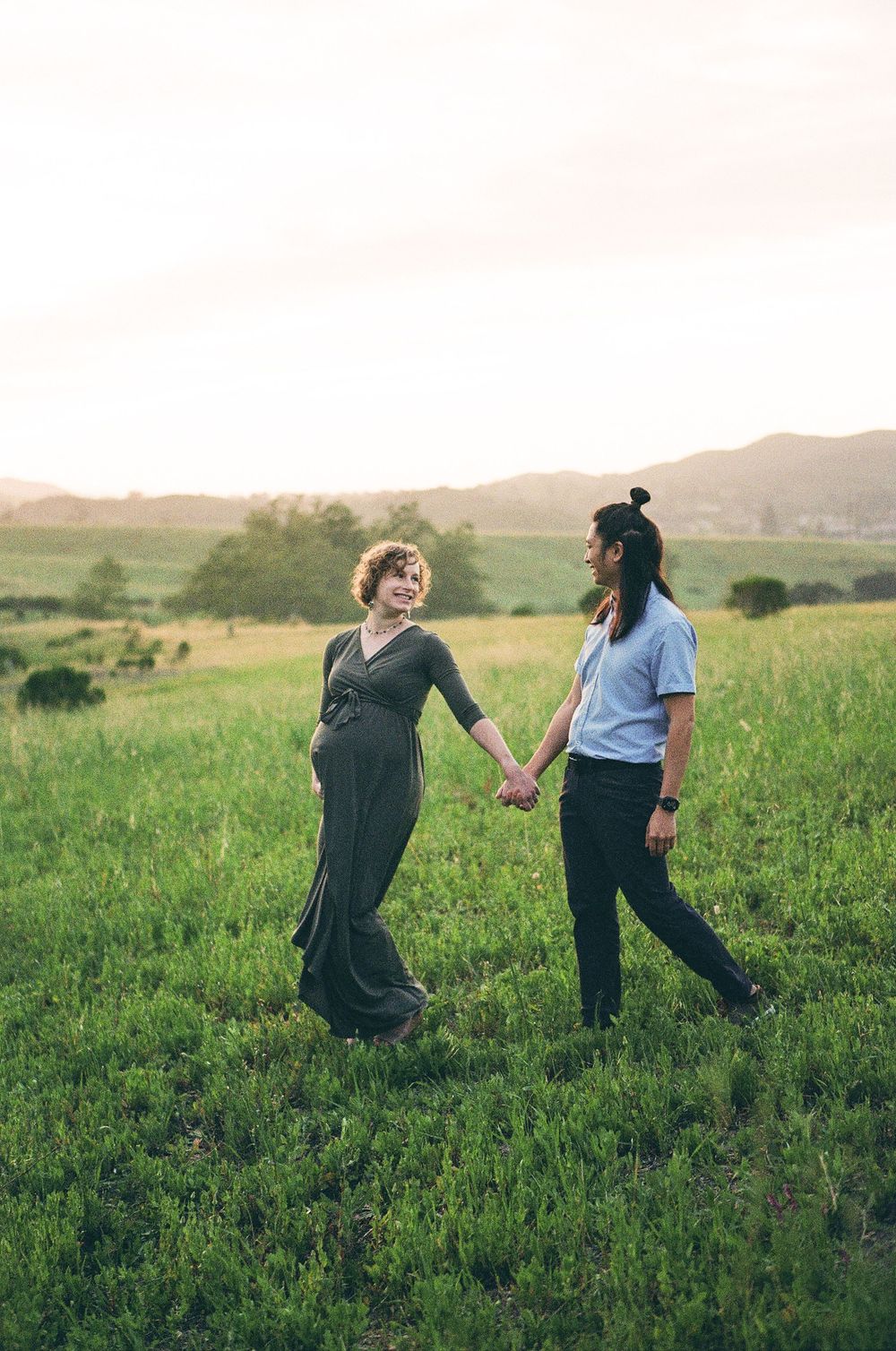 A couple walks in a green field captured on film photography