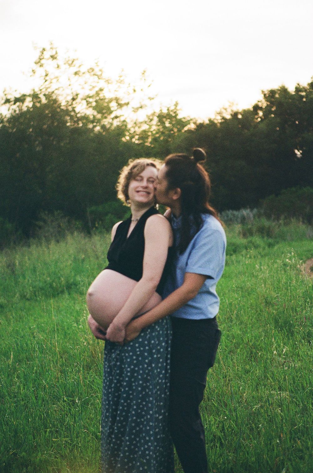 Film maternity photos in Santa Barbara California show a couple kissing while exposing bare pregnant belly in sweet film maternity session.