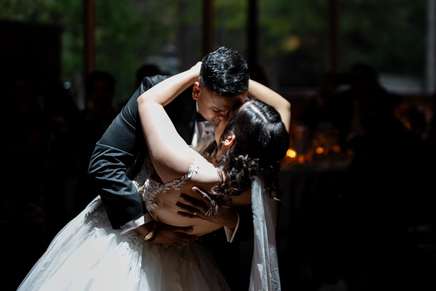 Couple sharing an intimate first dance embrace at their wedding reception in a dimly lit venue.