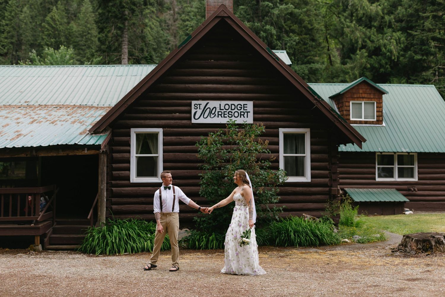 Rustic wooden cabin buildings nestled among green trees at a summer camp or mountain retreat.