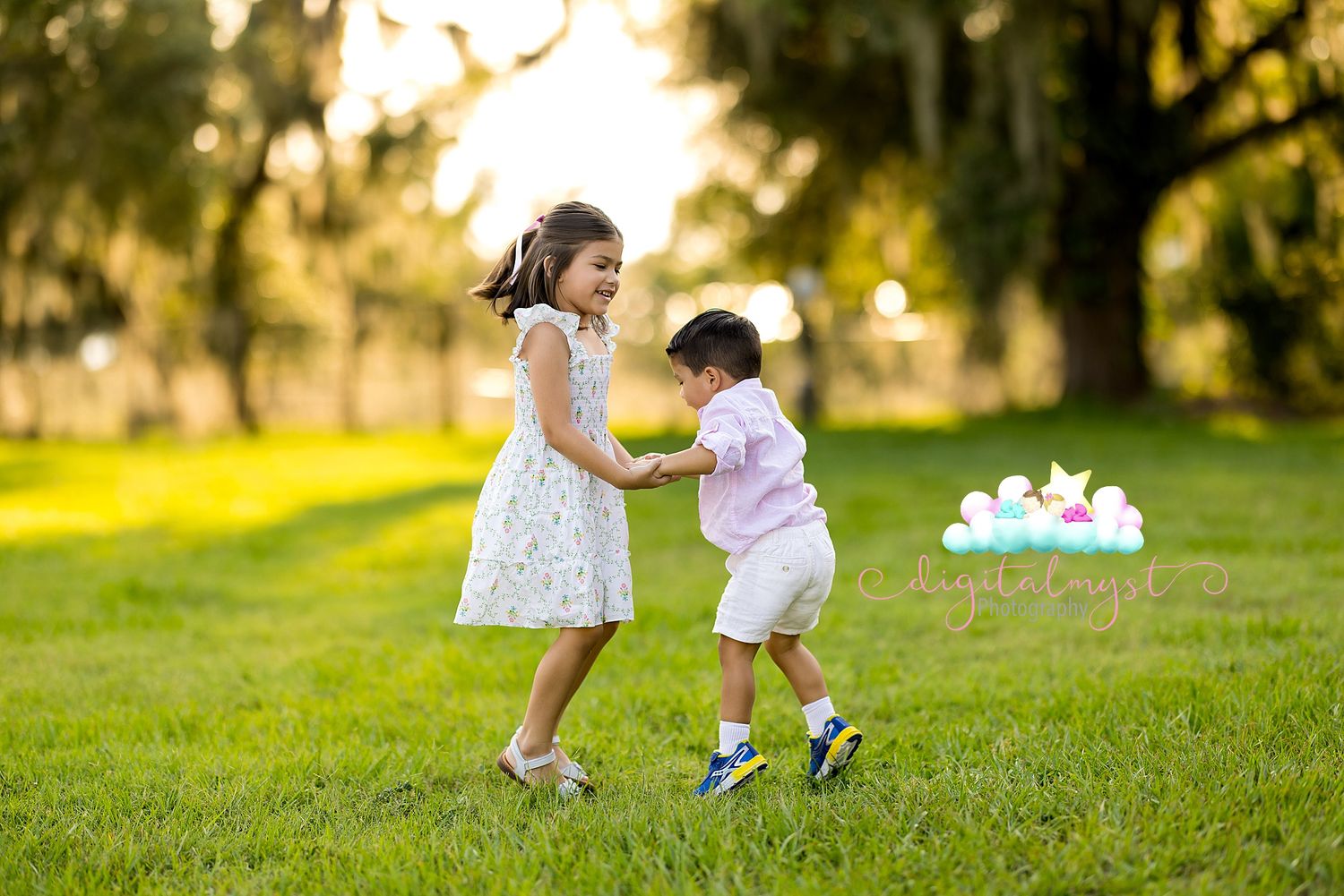 Two people playing and running together on a grassy hill during golden hour sunset.