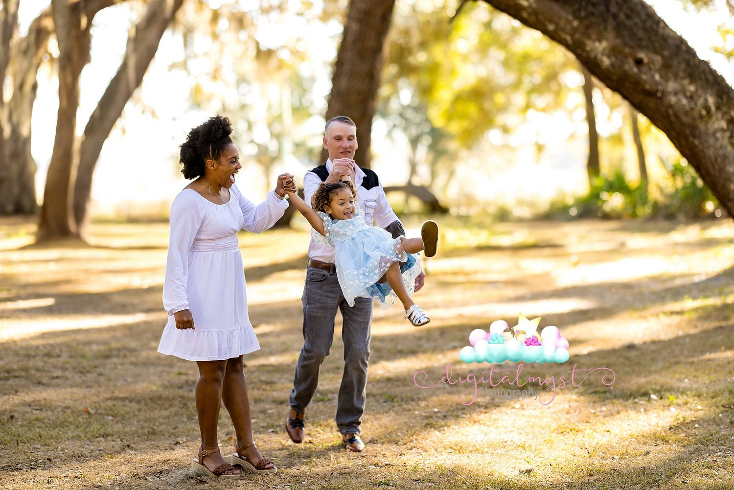 A family plays together in a sunlit park on an autumn afternoon with picnic supplies visible in the background.