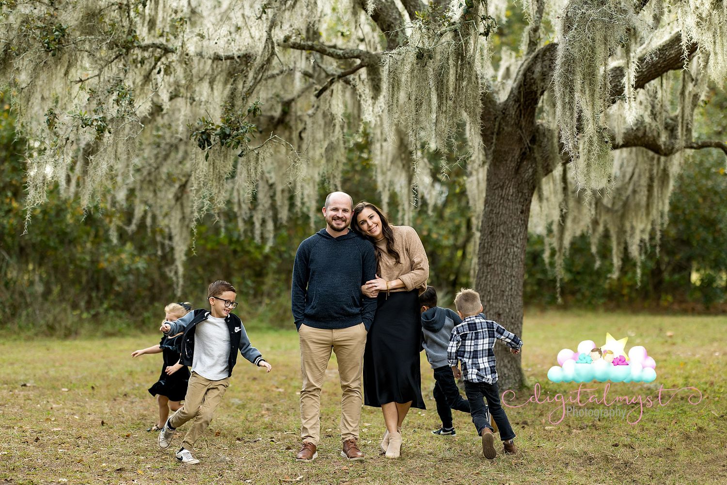 Group of people enjoying outdoor activities and playing games in a park with Spanish moss hanging from trees.
