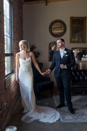 Elegant first look moment between couple in a rustic indoor venue with brick walls and natural light.
