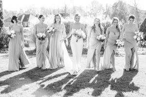 Wedding party in coordinating gray dresses posing together outdoors.