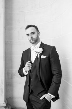 Classic black and white portrait of groom in three-piece suit with boutonniere.