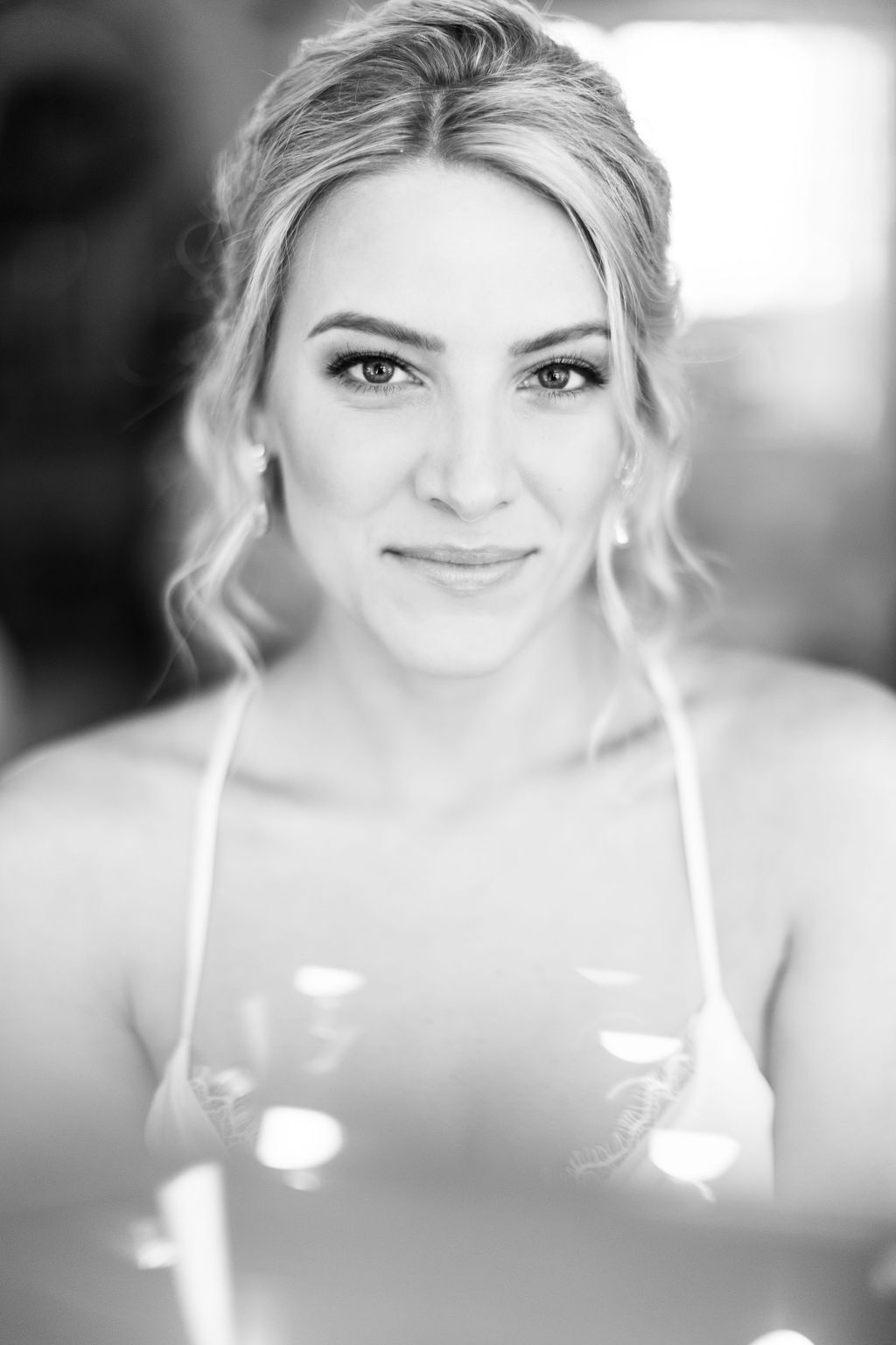 Black and white portrait of a smiling blonde woman with elegant updo hairstyle and natural makeup.