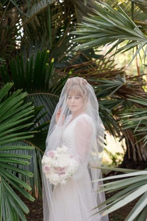 Bridal portraits among tropical palm fronds with soft natural lighting.