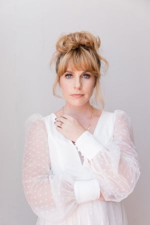 Studio portrait in soft white with delicate sheer sleeves and romantic styling.