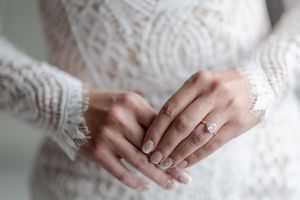 Close-up detail shots of hands wearing delicate lace sleeves and an elegant diamond engagement ring.