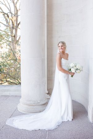 Classic bridal portraits taken between white pillars outdoors with natural lighting.