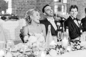 Wedding reception guests seated at long tables with candles and decor in an elegant brick-walled venue.
