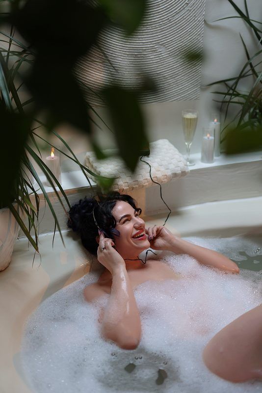 Relaxing bath scene with bubbles, champagne and greenery creating a luxurious spa-like atmosphere.