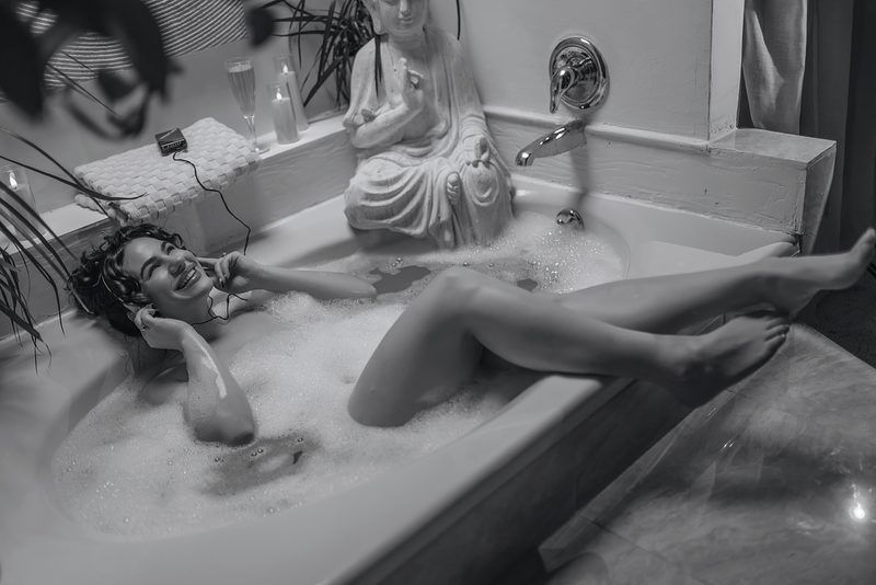Two people relaxing and enjoying a bubble bath in a vintage black and white photograph.