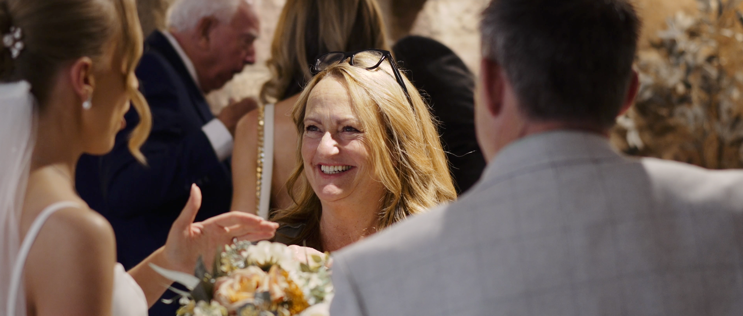 Elegant wedding celebration with guests dining and mingling at tables in rustic stone-walled venue.