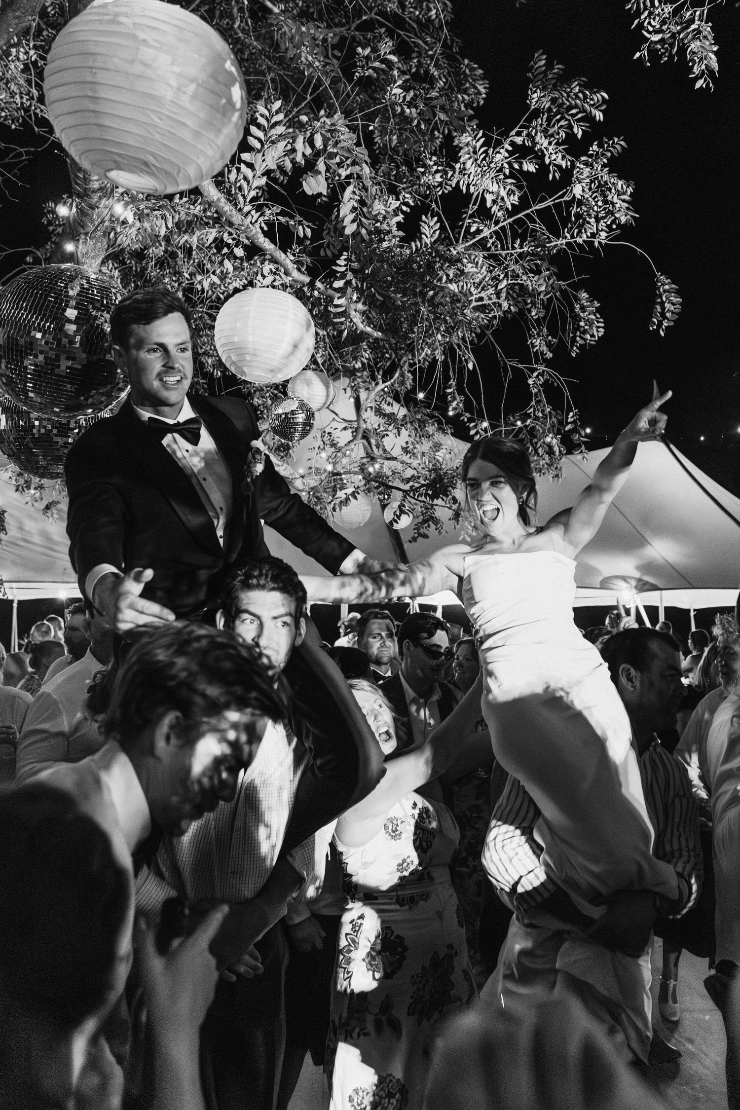 Bride and groom lifted up on shoulders on the dance floor at country wedding