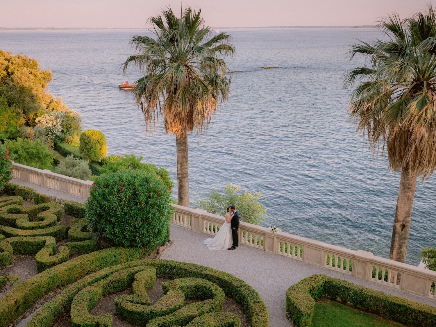 Italian-American couple arriving by boat at Isola del Garda for their wedding reception