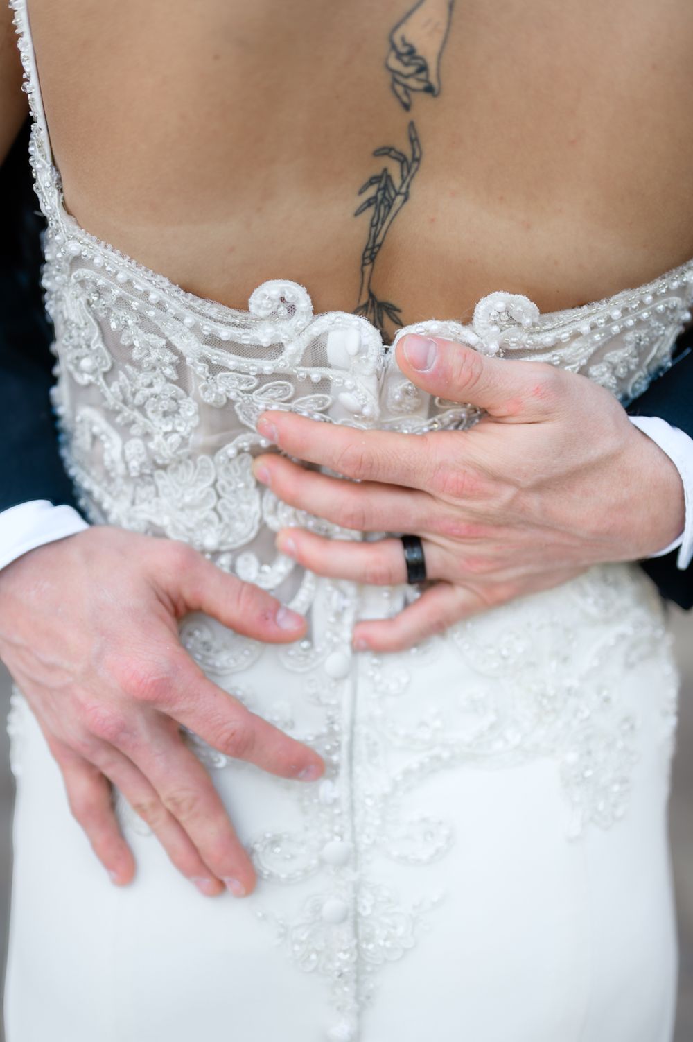 Close-up details of a bride's white lace wedding dress with delicate beading and embellishments.
