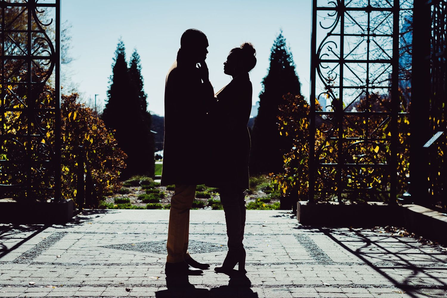 Silhouettes of people walking along a bridge or walkway during sunset with metal framework visible.
