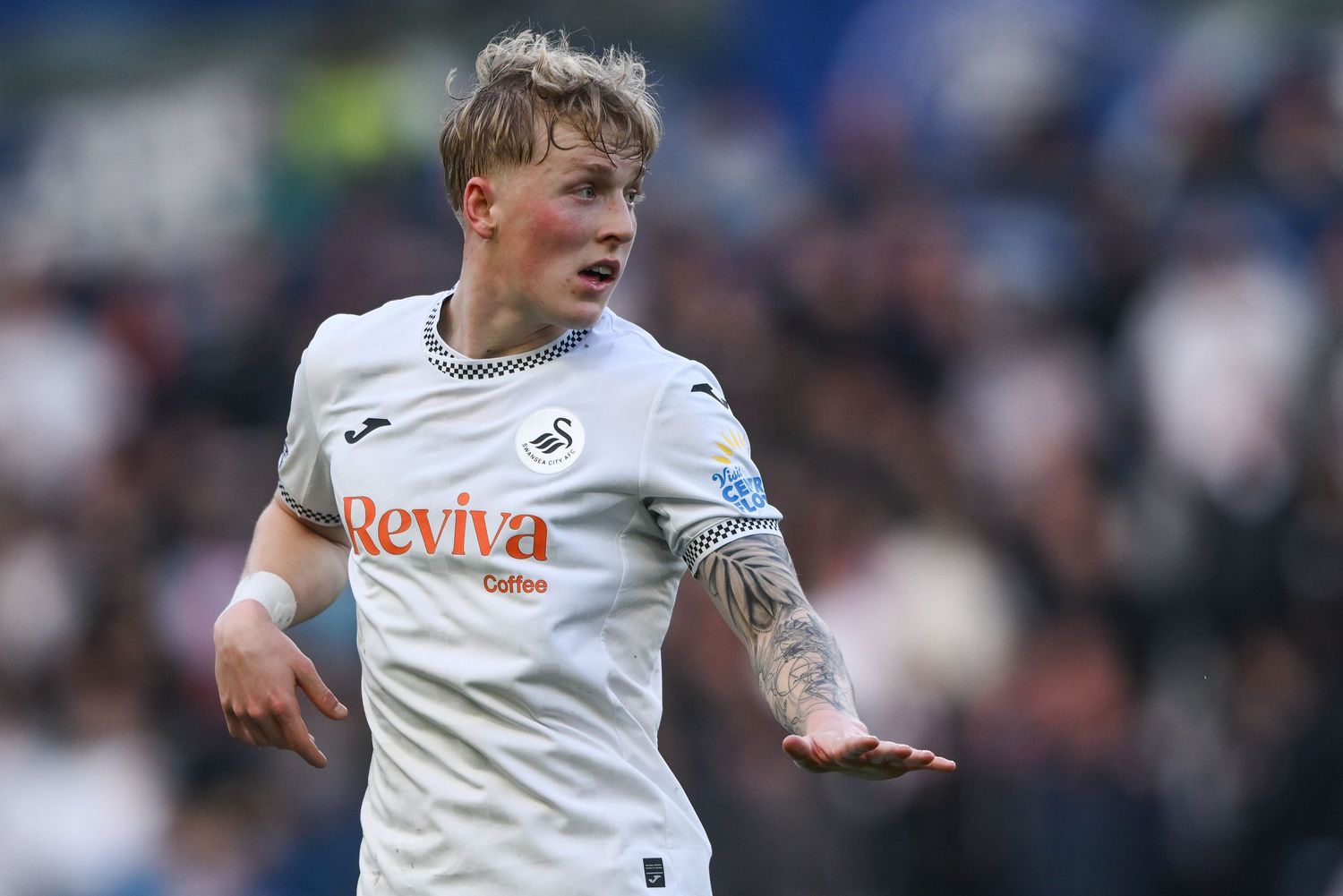 A soccer player in a white Swansea City jersey gestures during a match at the stadium.
