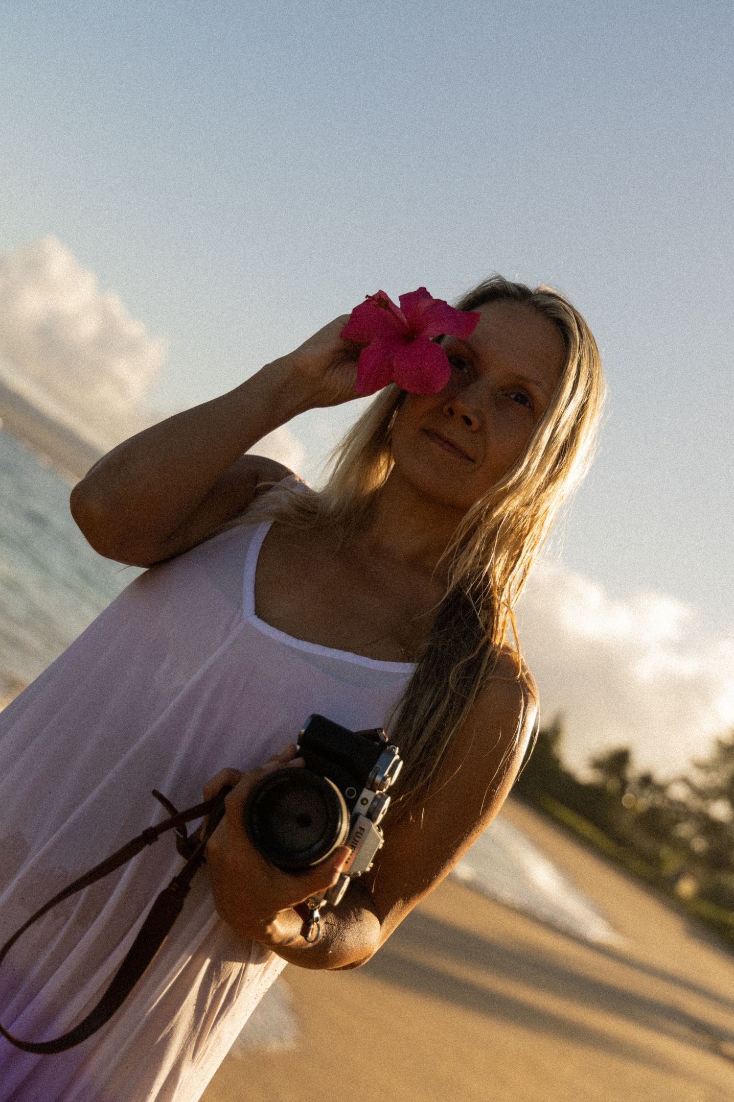 Photographer holding a Fujifilm camera during sunset on a North Shore Oahu beach.