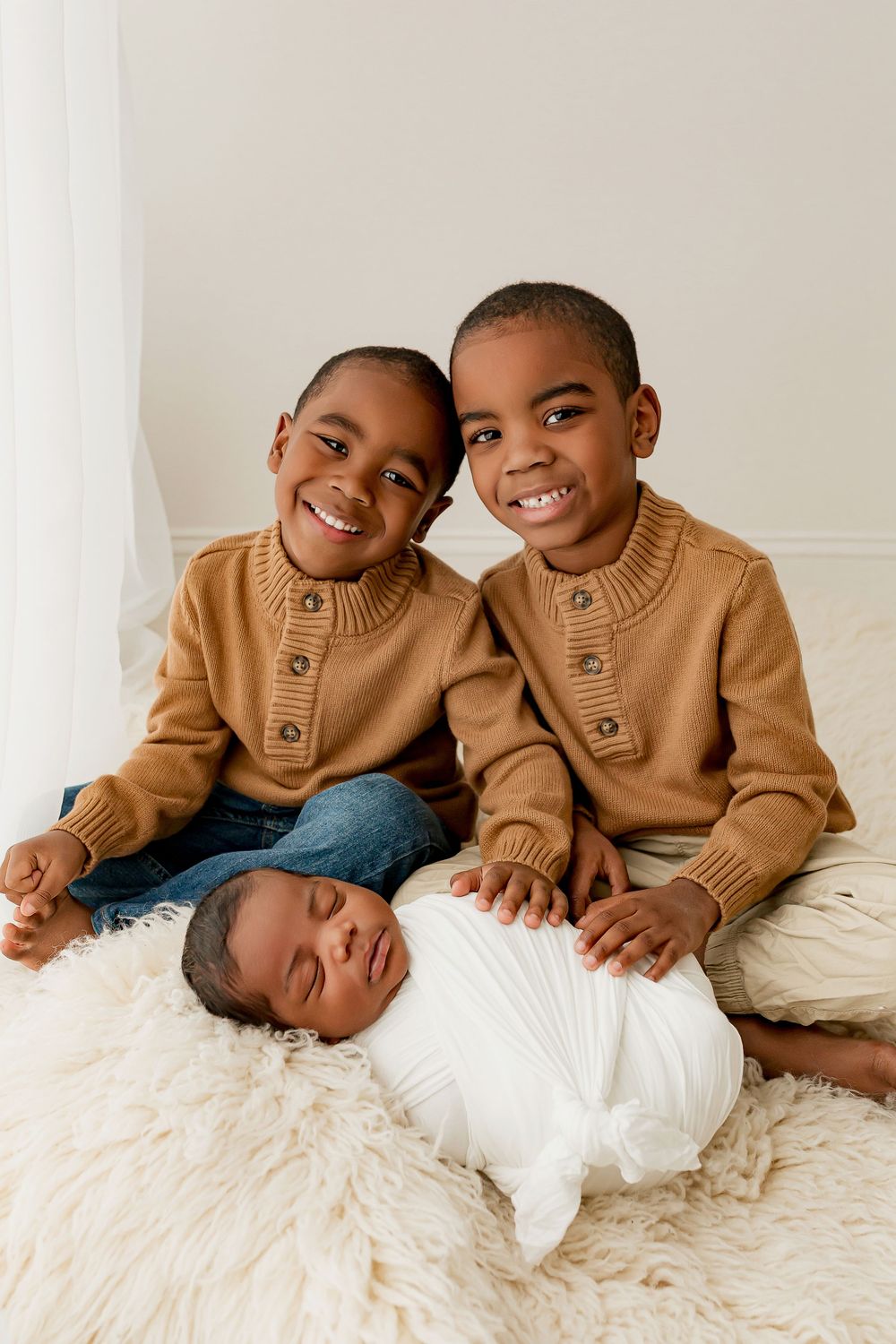 Two big brothers smiling with newborn baby sibling during Summerville SC studio session