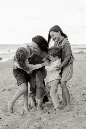 Children playing and tumbling together on a sandy beach in vintage black and white photograph.