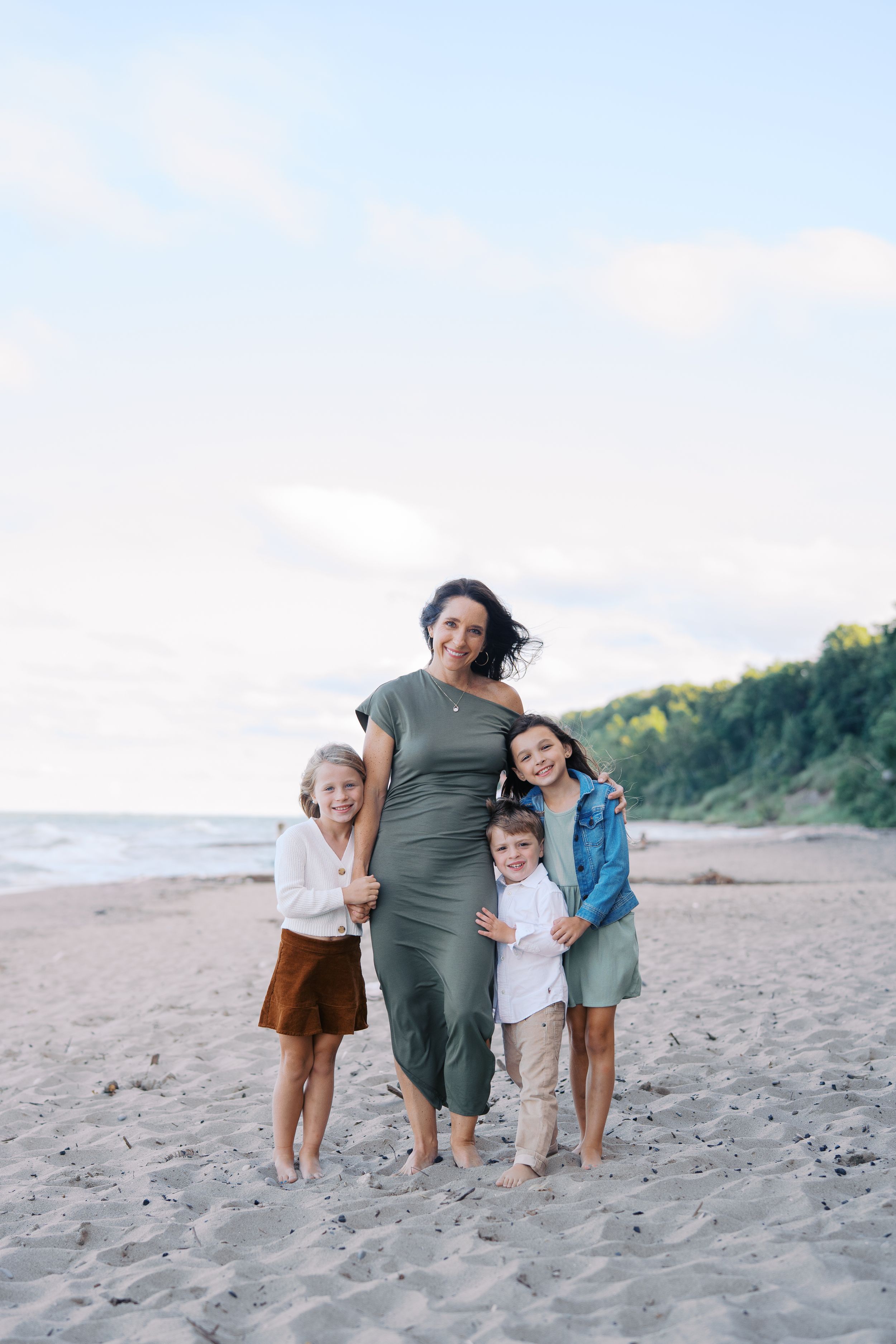 A family shares tender moments together while playing and embracing on a scenic beach at sunset.