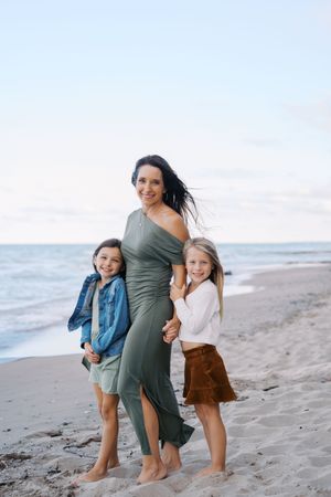 A family shares joyful moments together while walking along a sandy beach at sunset.