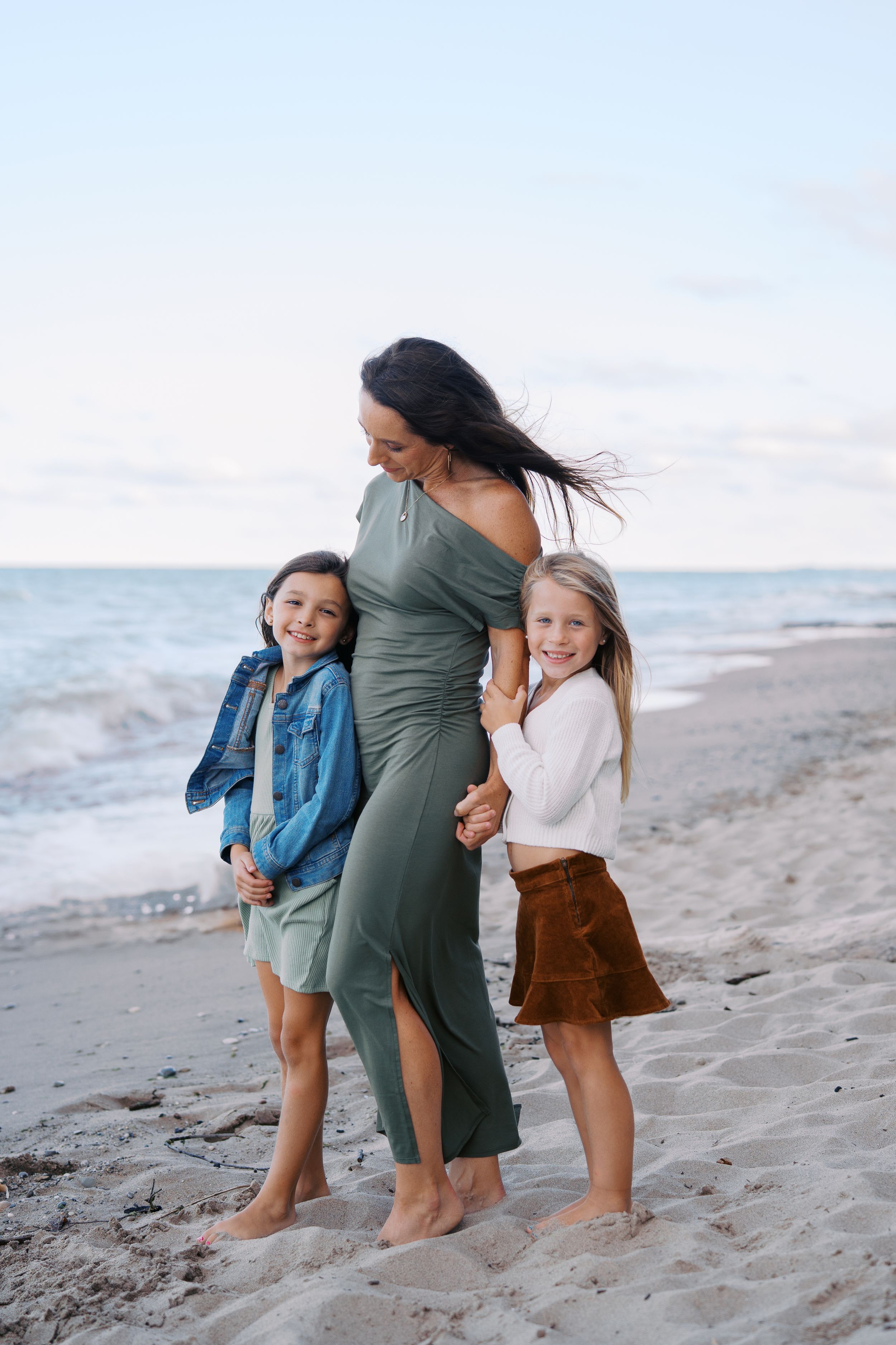 A family enjoying a casual stroll together along a sandy beach at sunset.