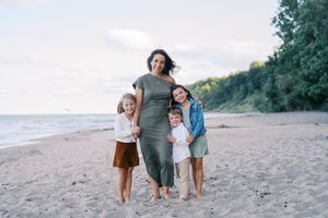 Family walking together on sandy beach at sunset while holding hands and enjoying quality time together.