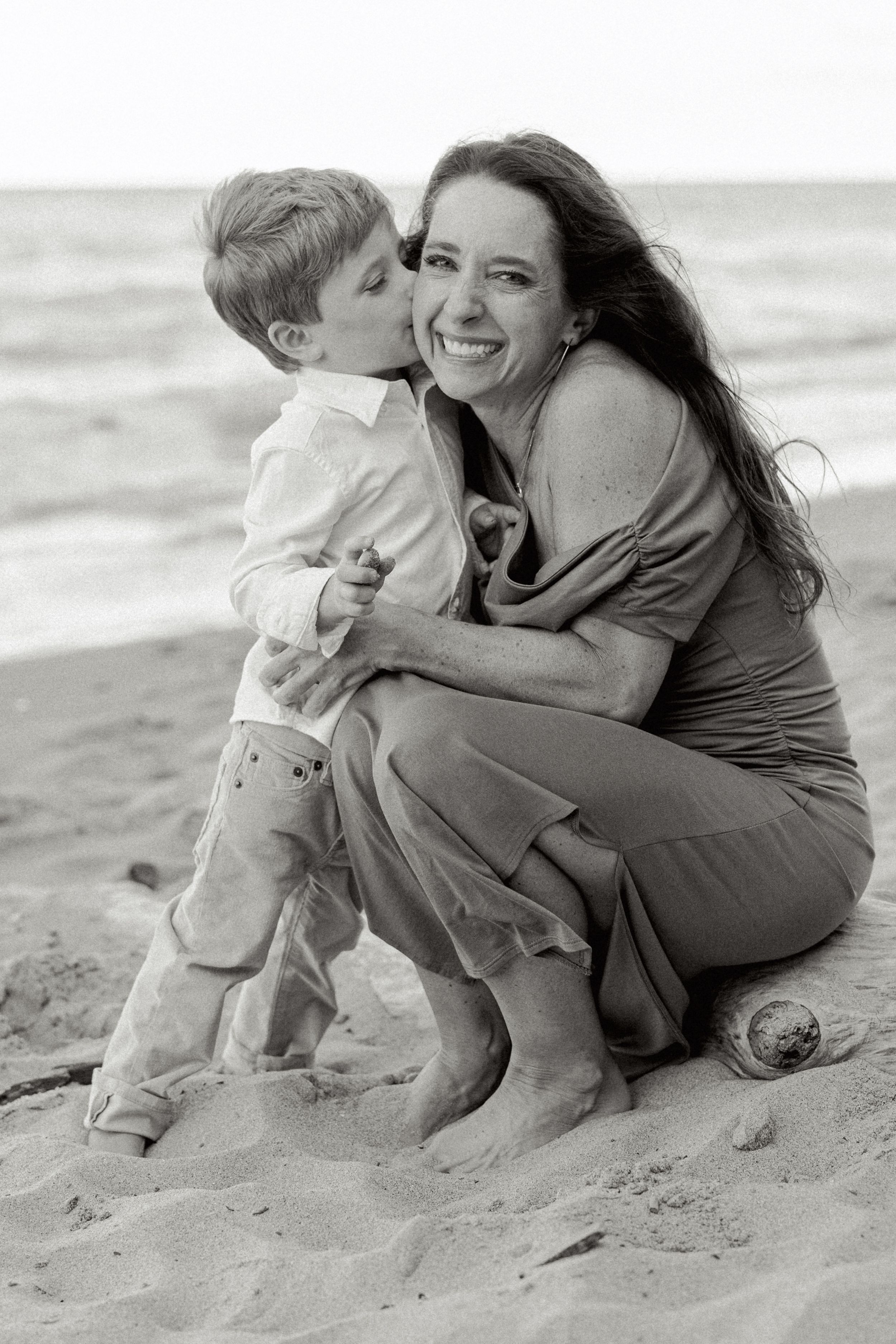 A heartwarming black and white photo of a parent and child sharing a joyful moment together on the beach.