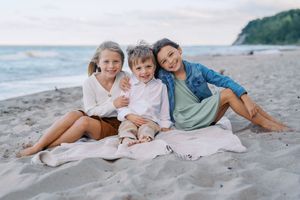 Family relaxing together on a sandy beach during sunset, creating a serene coastal scene.