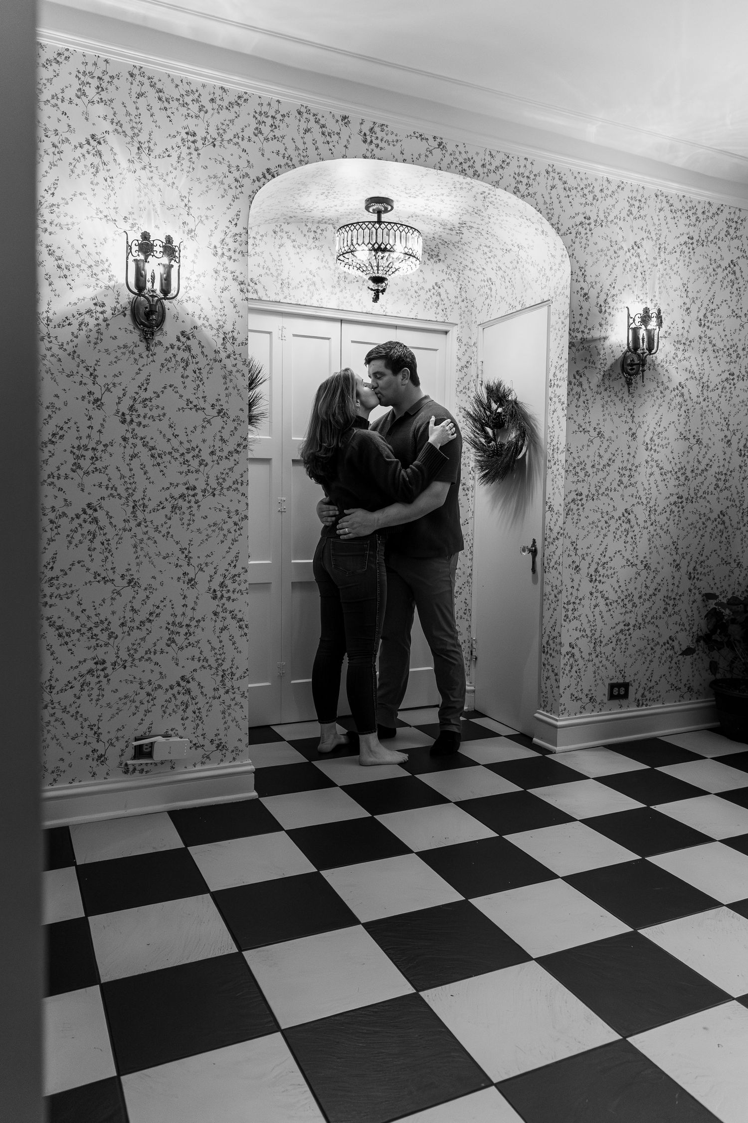 A sequence of black and white photos showing two figures embracing in a room with checkered floor and patterned wallpaper.