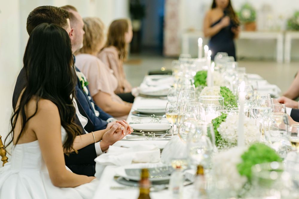 Guests listening to speech during wedding dinner with candlelight and floral table decor in Lisbon