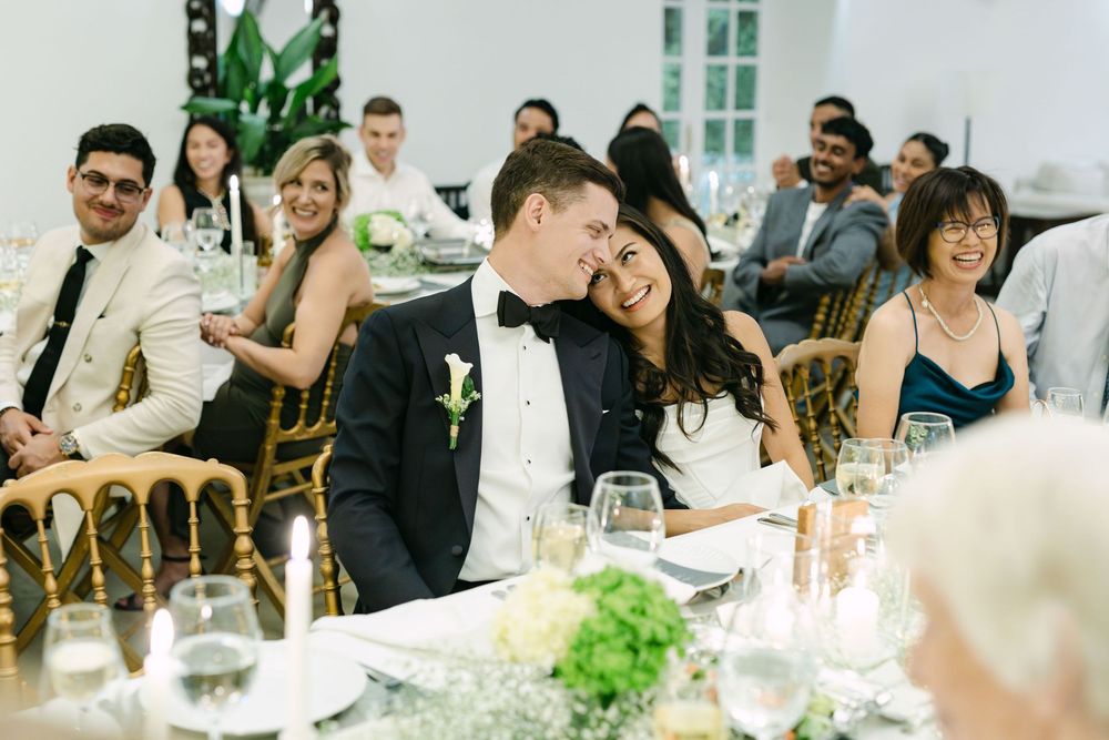 Bride and groom smiling and leaning together during speeches at wedding reception in Lisbon