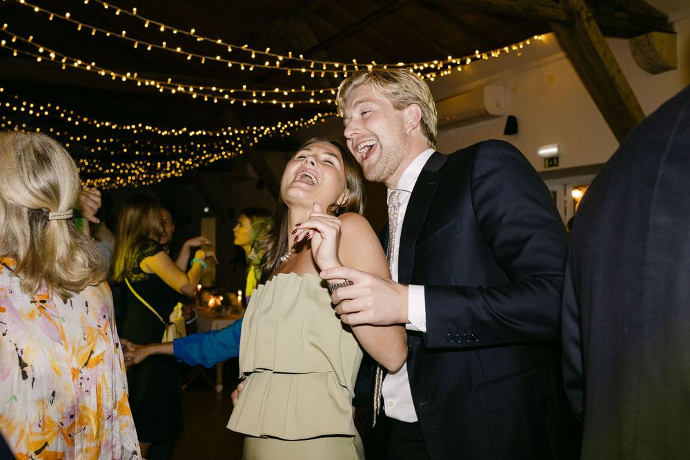 Guests dancing and singing together under fairy lights at wedding party in Quinta Nova do Hespanhol Lisbon