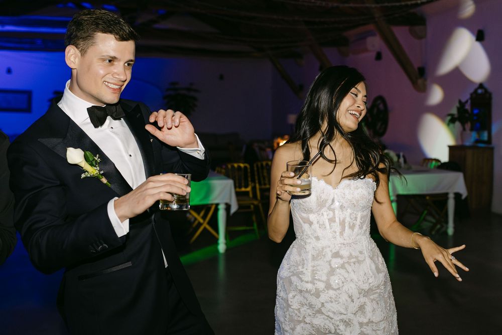 Bride and groom dancing with drinks in hand during lively wedding party in Lisbon Portugal