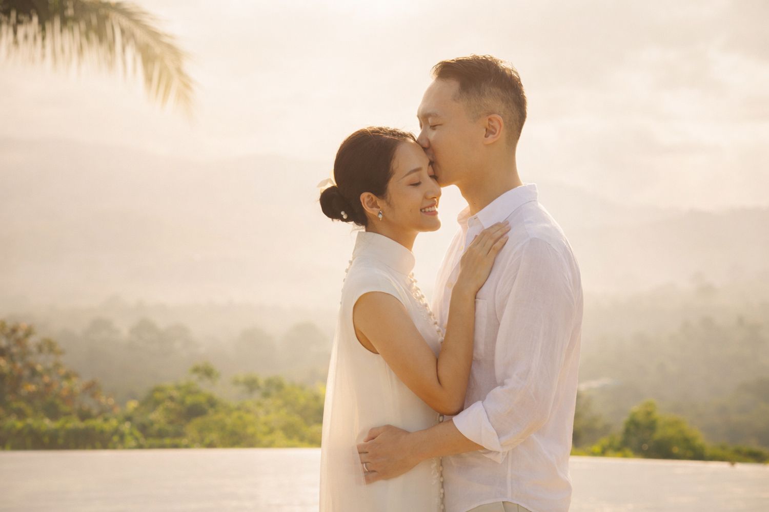 Refined sunrise portrait of an hk couple embracing poolside in Thailand, overlooking lush tropical landscape—intimate pre-wedding photos